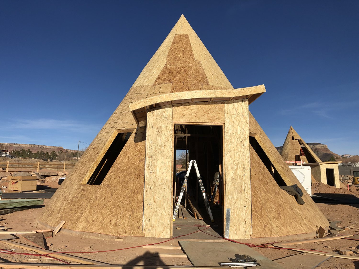 Front view of the fully rough-framed teepee with sheathing and its curved entrance